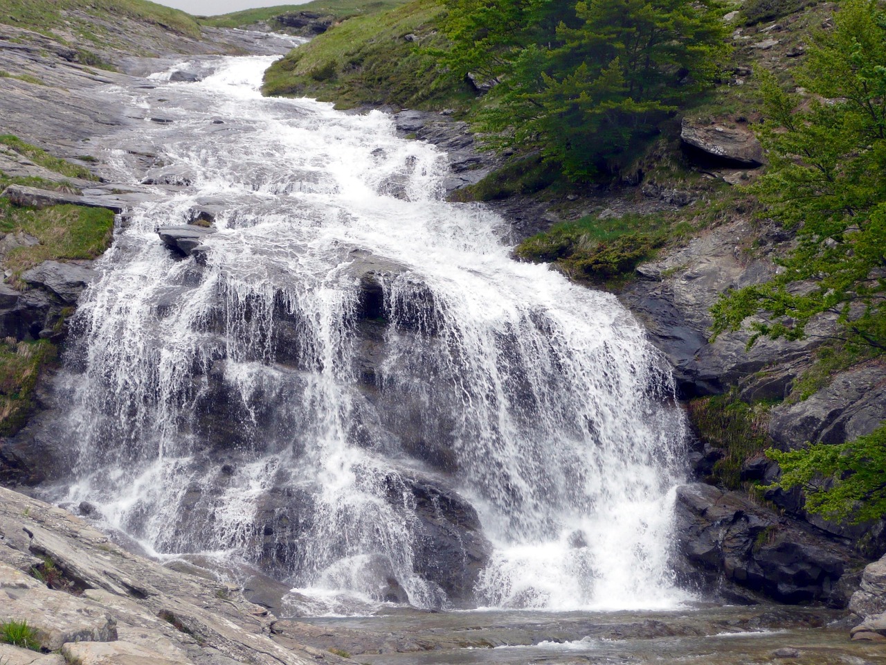Cascata alta in Italia, con acqua che scorre vigorosamente tra le rocce, immersa nella natura.