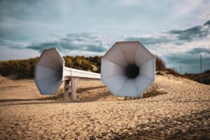 Spiaggia con sabbia che produce suoni melodici quando calpestata, circondata da cartelli di protezione.