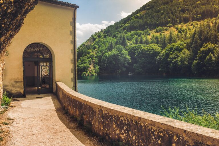 Lago di Vico circondato da boschi, con acque serene e cielo blu, ispirato dalla leggenda di Ercole.