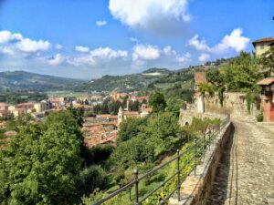 Vista panoramica delle mura venete che separano Bergamo Alta e Bassa, con strade pedonali affollate.
